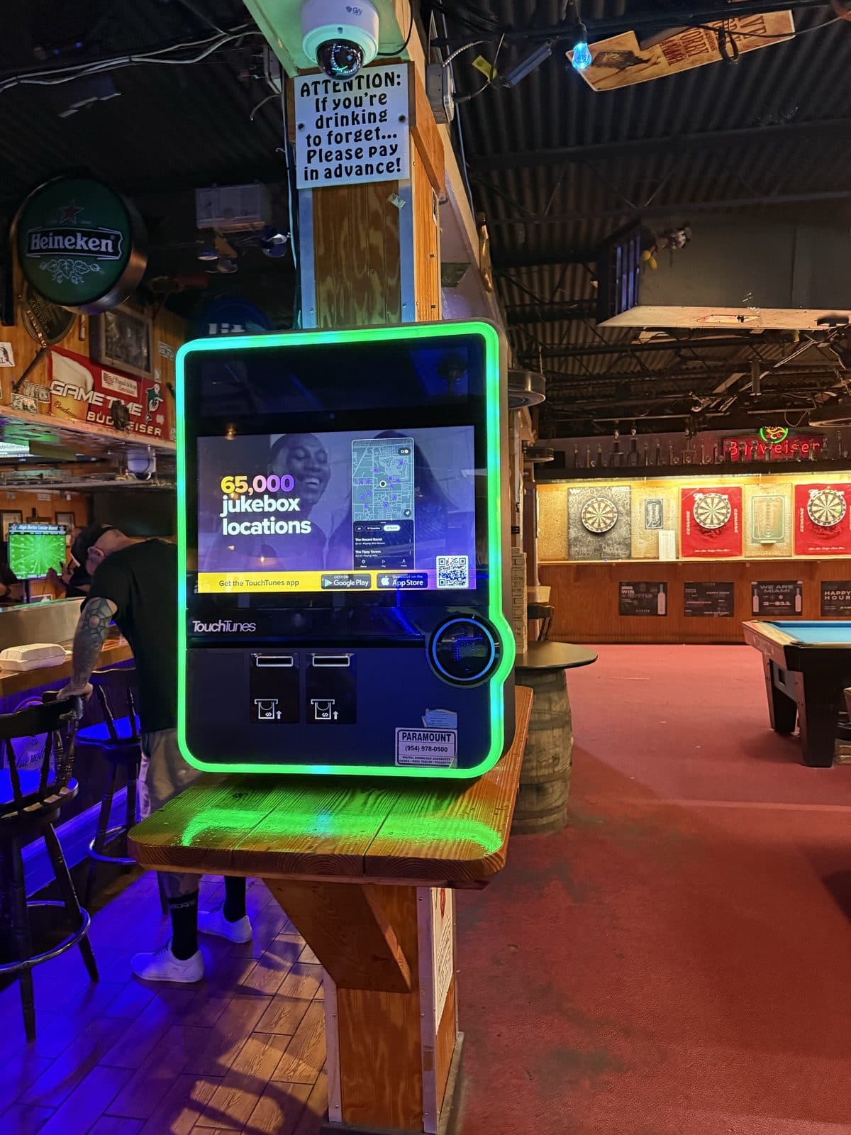 TouchTunes digital jukebox with the dart area in the background at Play By Play